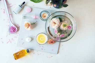 Pembe taze gül, çiçek yapraklı su, arka planda yanan mum, nazik vücut bakımı, aşk duygusu. 