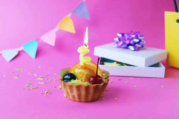 フルーツゼリーと燃えるキャンドルで飾られた誕生日カップケーキ 休日の装飾 ピンクの背景の贈り物 コピースペース — ストック写真
