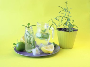 Limonata, nane yaprağı, tarhun ve salatalık dilimleri, parlak sarı bir zemin, sağlıklı içecekler, kilo vermek için su. 