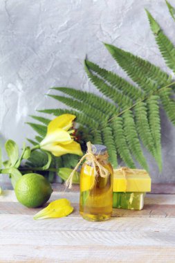 Doğal sabun, kireç, sarı zambak çiçeği, ahşap bir masada aromatik yağ, eğrelti otu yaprağı, spa, vücut bakımı ve rahatlaması için organik kozmetik ürünler.
