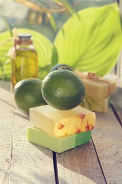 Doğal sabun, kireç, sarı zambak çiçeği, ahşap bir masada aromatik yağ, eğrelti otu yaprağı, spa, vücut bakımı ve rahatlaması için organik kozmetik ürünler.