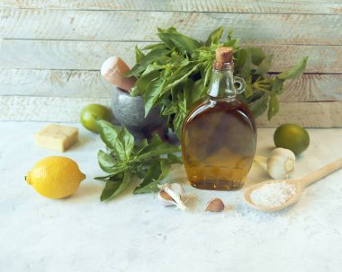Mutfak masasında pesto sosu, fesleğen yaprağı, zeytinyağı, sarımsak, tuz, peynir ve turta yapmak için gerekli malzemeler. 