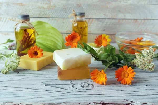 Calendula flowers, soap, oils and tinctures, on a wooden background, natural ingredients, alternative medicine