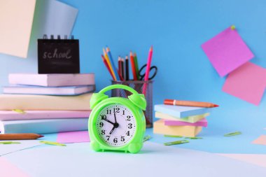 Alarm clock, books and stationery on pastel colors background of colorful paper, back to school, education, student study table, blur focus, copy space