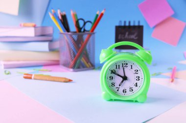 Alarm clock, books and stationery on pastel colors background of colorful paper, back to school, education, student study table, blur focus, copy space