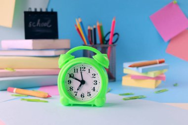 Stationery, alarm clock, books on a background of pastel colors of multi-colored paper, back to school, education