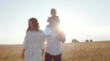 Buğday tarlasında kızı olan neşeli mutlu bir aile birlikte doğanın tadını çıkarıyor..