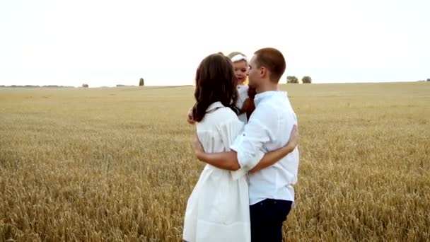 Recreación familiar de verano al aire libre: madre, padre e hija se abrazan en el prado. — Vídeos de Stock