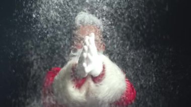 Pozitif aktif Noel Baba kırmızı giysiler içinde dans ediyor ve parlak kar atıyor..