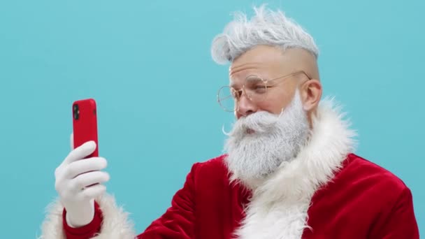 Jultomten önskar Gott Nytt År, God Jul med hjälp av smartphone videosamtal — Stockvideo