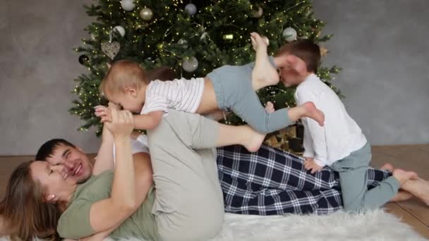快乐的父母在圣诞树下和快乐的孩子玩耍. — 图库视频影像