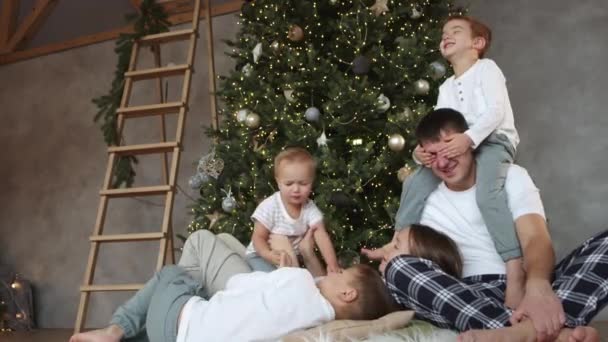 Щаслива сім'я сидить разом біля святкової ялинки в затишному сучасному будинку . — стокове відео
