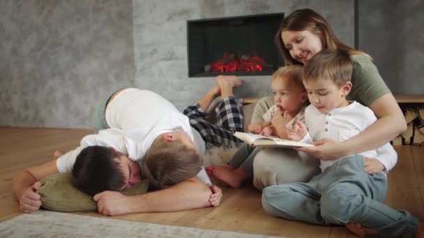 Familia feliz juntos, padres cariñosos leer libro de cuentos de hadas a los niños lindos en el hogar — Vídeo de stock