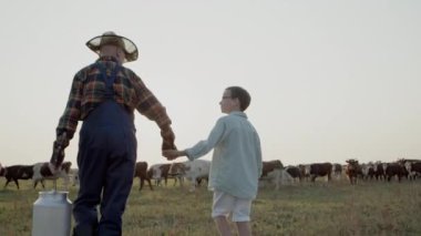 Neşeli bir çocuk ve yaşlı bir çiftçinin el ele tutuşup otlakta yürüdüğünü hayal edin..