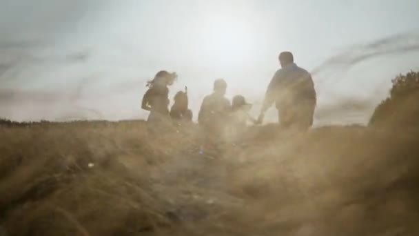 Vue arrière de la famille sur le champ de blé au coucher du soleil s'amuser ensemble dans la nature. — Video