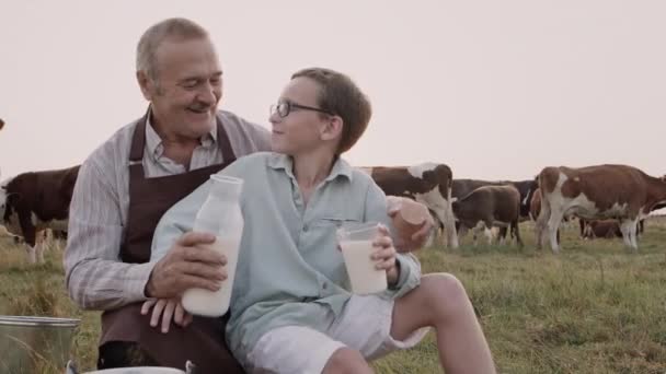 Happy grandfather, kid grandson drink fresh healthy natural cow milk outdoors — Stockvideo