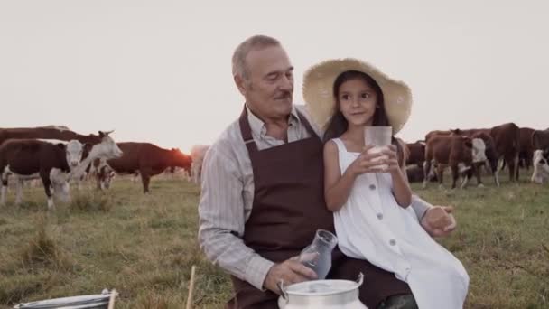 Happy grandfather, child granddaughter drink healthy natural cow milk outdoors — Stock Video