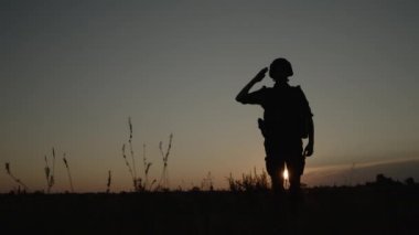 Sahada, savaşta ve orduda gün batımında asker selamlaması silueti..