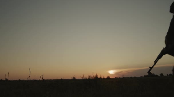 Infantería en casco con rifle apuntando a fuerzas hostiles al atardecer en el campo. — Vídeo de stock