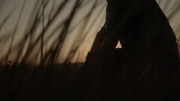 Close up vista laterale del cecchino in casco seduto in erba e mirare al nemico. — Video Stock