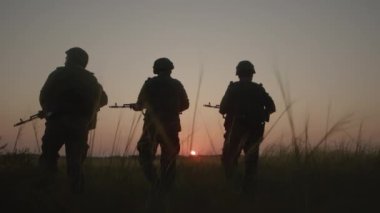 Silahlı ve kamuflaj üniformalı cesur askerler saha gerisine gider..