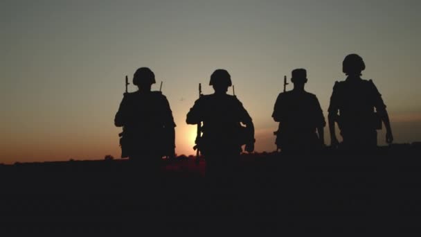 Two armed men with weapon walking across field after combat operation back view. — Stock Video