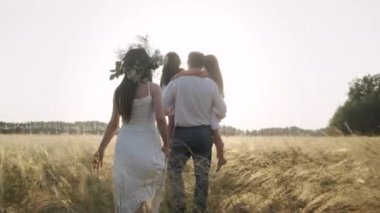 Kızları olan mutlu ebeveynler yazın sarı tarlada eğleniyorlar..