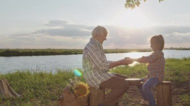 Smiling affectionate old grandmother and little granddaughter together play funny game holding hands in sunshine outdoors. Summer family walk, happy carefree childhood, life in love, joy and peace