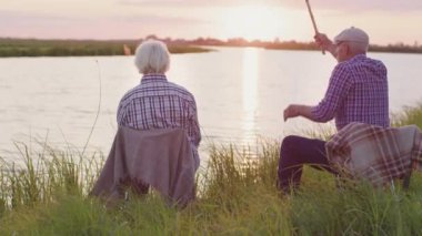Happy old couple together embracing sitting on lake beach in sunshine outdoors. Candid affectionate feelings, live joyful human emotions, real harmony love, tenderness and care of two retired lovers