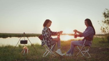 Two girls practice pair stretching, synchronously doing free leg raises standing at hands, sport exercise near water on boardwalk outdoors. Kid gymnastics together for healthy lifestyle, flexible body