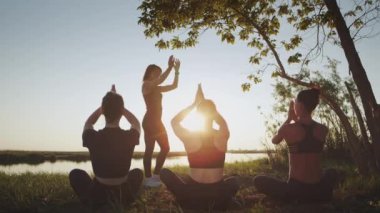 Çeşitli üç sakin kadın grubu senkronize bir şekilde yoga egzersizi yapıyor. Nilüfer pozisyonu almış açık denizde birlikte oturuyorlar. Enerji dengesi için Asana, zihinsel sağlık, uyum.
