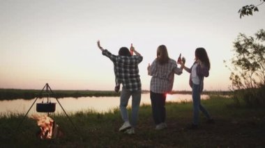 Diverse group of five happy women does together sitting in lotus position on meadow, enjoys harmony outdoors in sunshine. Training lesson for body relax, calm mind, wellness in forest park