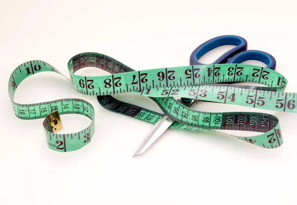 Green measuring tape and scissors — Stock Photo, Image
