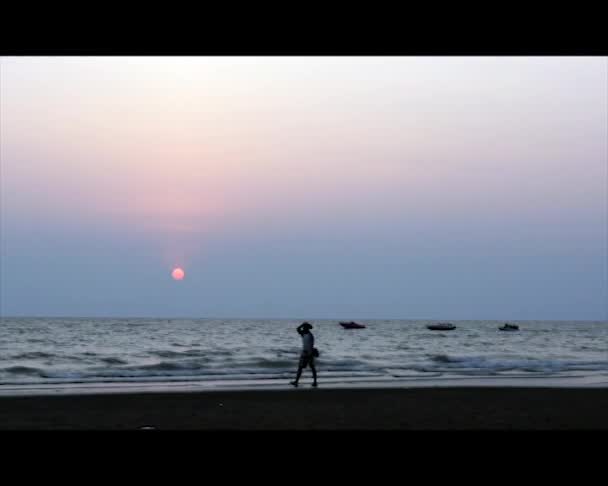 Menschen gehen und ruhen am tropischen Meer bei Sonnenuntergang — Stockvideo