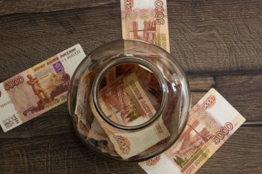 Nakit para cam kavanozda, ahşap bir masada, düz yatıyordu.