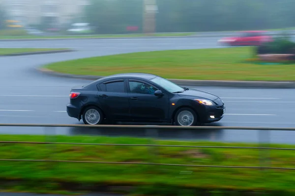 霧の多い夏の日に濡れたアスファルトの街の路上で車を運転 — ストック写真