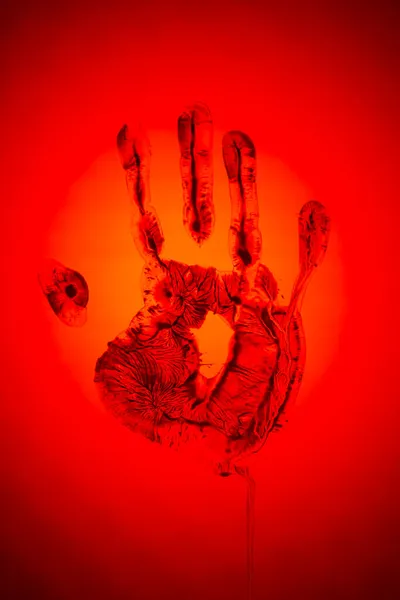 Evil red human palm imprint on red backdrop as sign of danger and warning