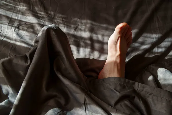 Perna Homem Dormindo Destaca Cobertor Cama Raios Sol — Fotografia de Stock