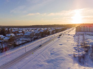 Kışın gün batımında, küçük ve yüksek binalı karlı şehir manzarası. Petrozavodsk şehri, Rusya