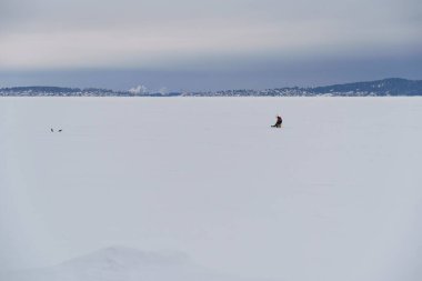 Kışın donmuş gölde balıkçı. Köyün yakınlarında buzda balık tutarken.