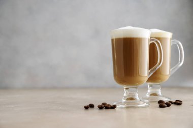 Bardakta kahve? Tarafsız arka planda kremalı süt köpüğüyle. Boşluğu kopyala