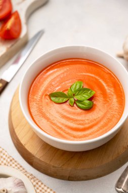 Beyaz kaselerde taze fesleğenli domates çorbası. Parlak bir arka plan. Vejetaryen kremalı çorba.