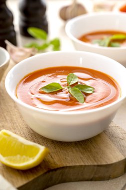 Beyaz kaselerde taze fesleğenli domates çorbası. Parlak bir arka plan. Vejetaryen kremalı çorba.