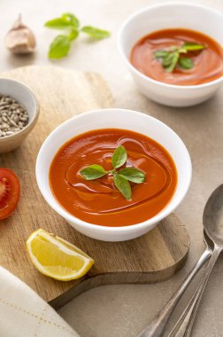 Beyaz kaselerde taze fesleğenli domates çorbası. Parlak bir arka plan. Vejetaryen kremalı çorba, kopyalama alanı.
