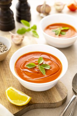 Beyaz kaselerde taze fesleğenli domates çorbası. Parlak bir arka plan. Vejetaryen kremalı çorba.