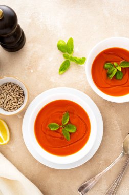 Beyaz kaselerde taze fesleğenli domates çorbası. Parlak bir arka plan. Vejetaryen kremalı çorba, kopyalama alanı.