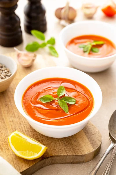 Beyaz kaselerde taze fesleğenli domates çorbası. Parlak bir arka plan. Vejetaryen kremalı çorba.