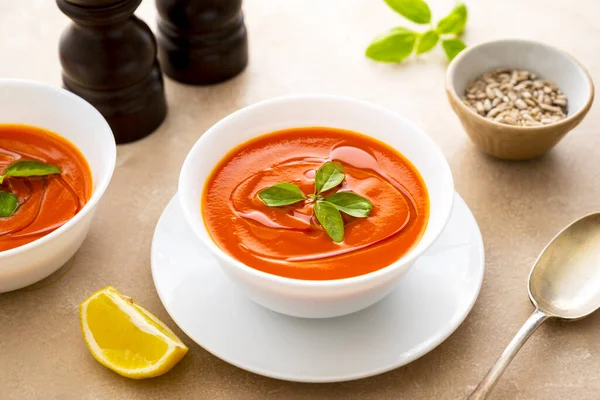 Beyaz kaselerde taze fesleğenli domates çorbası. Parlak bir arka plan. Vejetaryen kremalı çorba.
