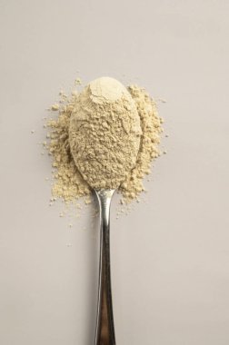 heap of protein powder with plastic spoon isolated on white