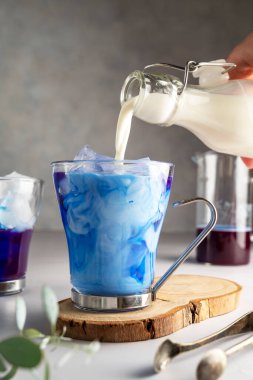 Mavi bezelyeli buzlu latte. Buzlu cam bardakta mavi kibrit sütlü latte. Yaz mavisi içki